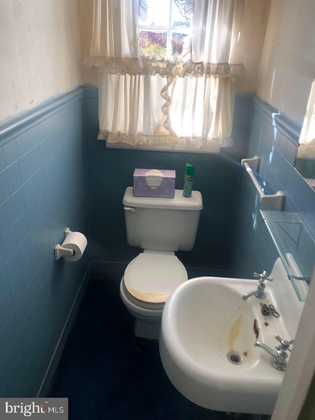 bathroom with sink, toilet, and tile walls