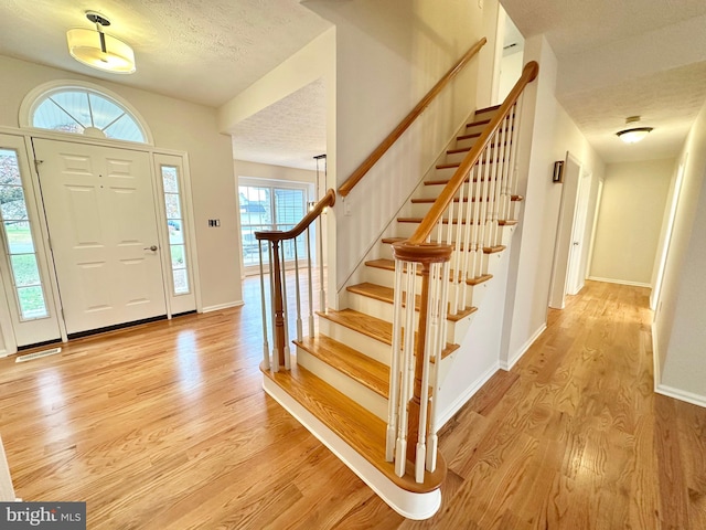 foyer with a textured ceiling and light hardwood / wood-style flooring