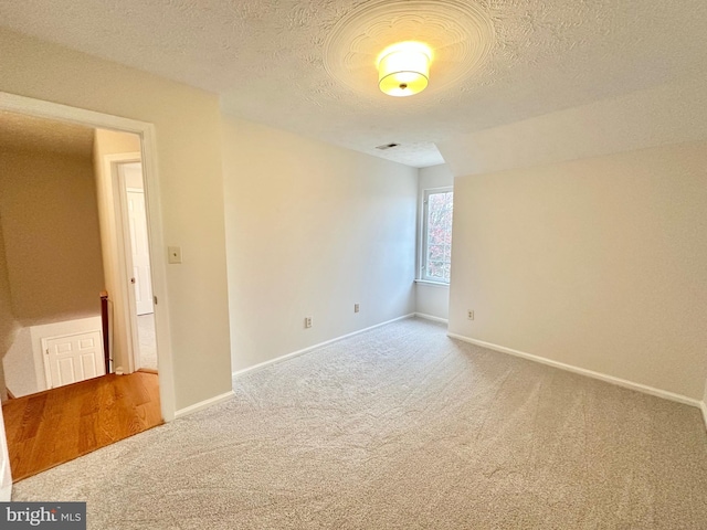 carpeted empty room with a textured ceiling