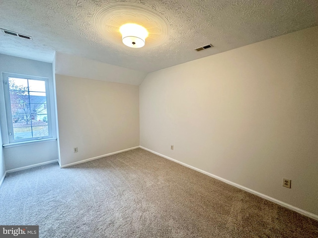 empty room featuring carpet, a textured ceiling, and vaulted ceiling