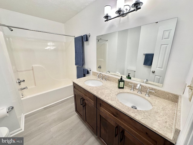 full bathroom with shower / tub combination, wood-type flooring, a textured ceiling, and toilet