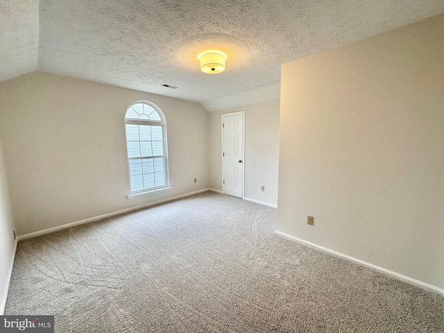 carpeted spare room featuring a textured ceiling and lofted ceiling