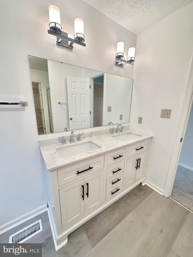 bathroom featuring hardwood / wood-style floors, vanity, and a textured ceiling