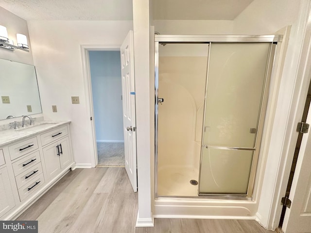 bathroom featuring hardwood / wood-style floors, vanity, a textured ceiling, and walk in shower