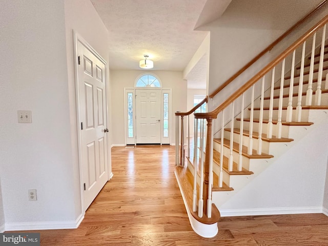 foyer entrance featuring a textured ceiling and light hardwood / wood-style floors