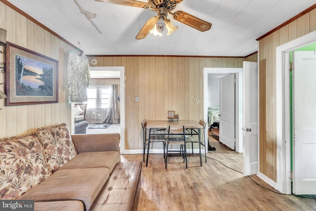 living room with wood walls, ceiling fan, and light hardwood / wood-style floors