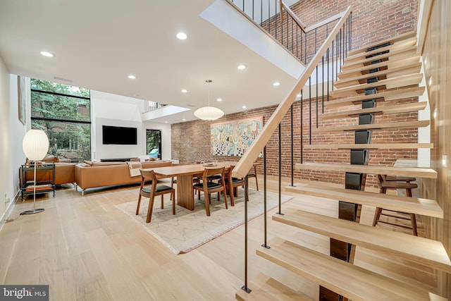 dining room with expansive windows, wood-type flooring, and brick wall