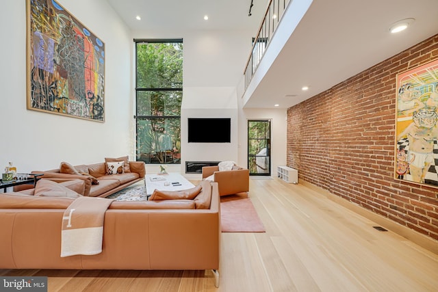 living room featuring light hardwood / wood-style floors, brick wall, and a wall of windows