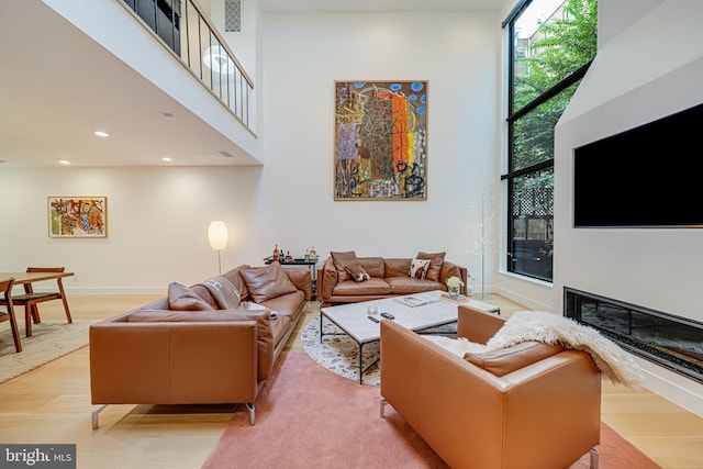 living room with a towering ceiling and light hardwood / wood-style flooring