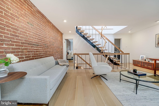 living room featuring a skylight, brick wall, and light hardwood / wood-style floors