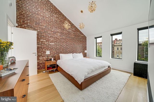 bedroom featuring high vaulted ceiling, brick wall, and light hardwood / wood-style floors