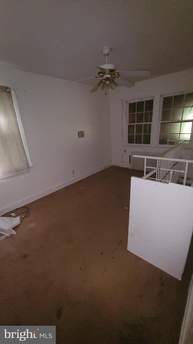 empty room featuring ceiling fan and dark carpet