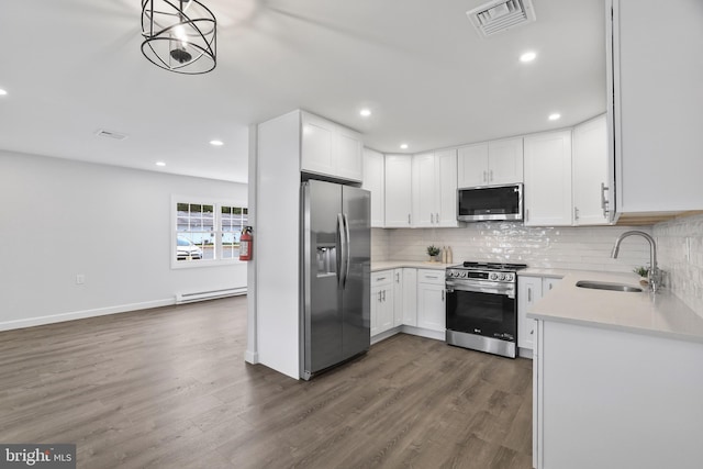 kitchen featuring appliances with stainless steel finishes, baseboard heating, dark wood-type flooring, sink, and white cabinetry