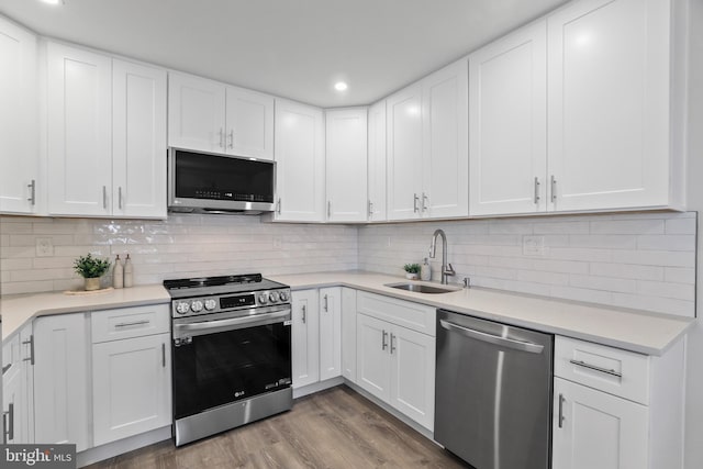 kitchen with backsplash, sink, light hardwood / wood-style floors, white cabinetry, and stainless steel appliances