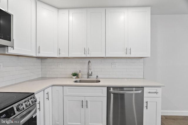 kitchen featuring tasteful backsplash, stainless steel appliances, sink, wood-type flooring, and white cabinetry