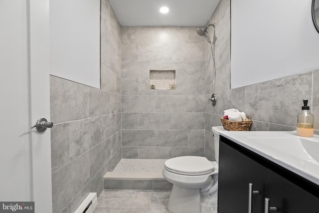 bathroom featuring a tile shower, a baseboard radiator, toilet, vanity, and tile walls