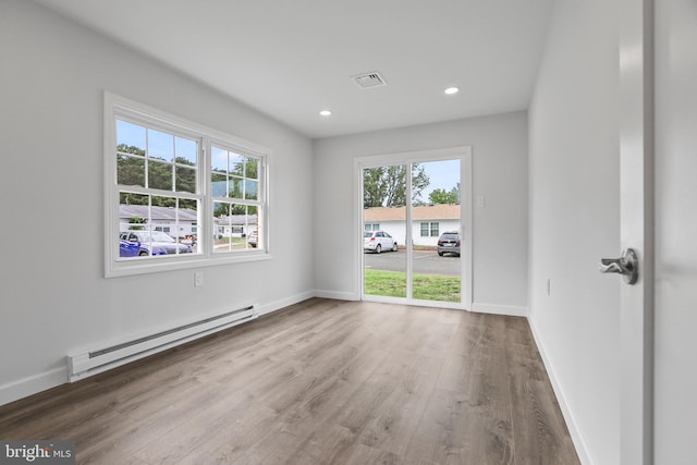 spare room featuring wood-type flooring and a baseboard radiator