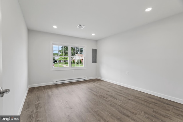 spare room with hardwood / wood-style floors, electric panel, and a baseboard heating unit