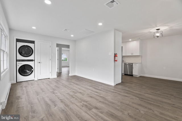 laundry room featuring a baseboard heating unit, light wood-type flooring, and stacked washer and clothes dryer