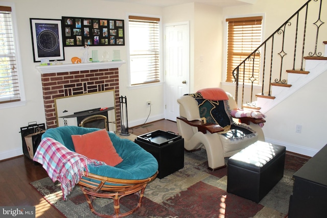 living room featuring plenty of natural light, dark hardwood / wood-style flooring, and a brick fireplace