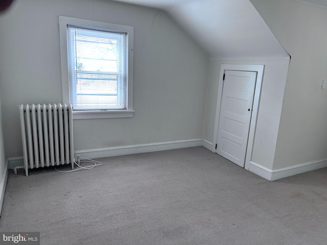 additional living space with light colored carpet, radiator, and lofted ceiling