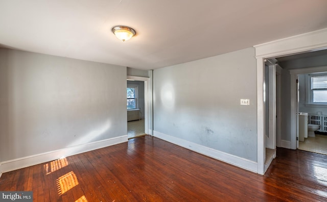 spare room with dark hardwood / wood-style flooring and a wealth of natural light