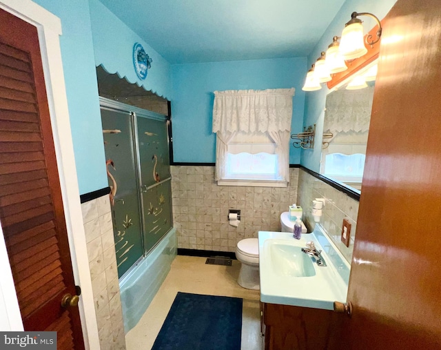 full bathroom with toilet, vanity, tile walls, and combined bath / shower with glass door