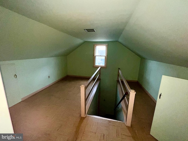 bonus room with light parquet flooring and vaulted ceiling