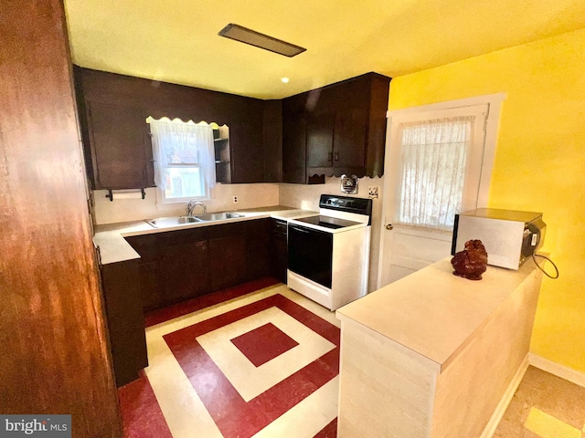 kitchen featuring dark brown cabinets, electric range, plenty of natural light, and sink