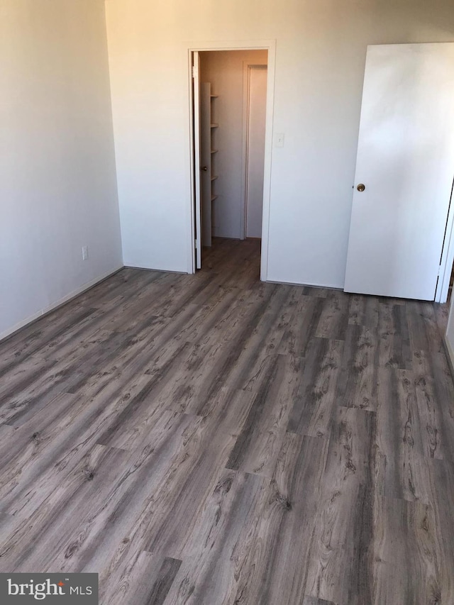 unfurnished bedroom featuring dark hardwood / wood-style floors, a spacious closet, and a closet