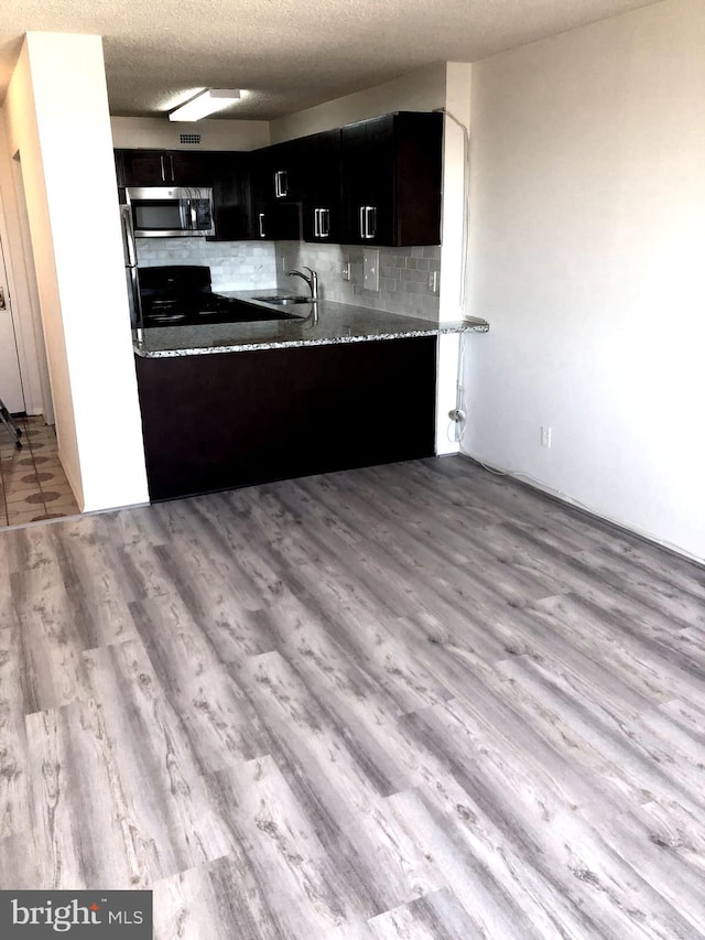 kitchen with a textured ceiling, tasteful backsplash, light hardwood / wood-style flooring, and sink