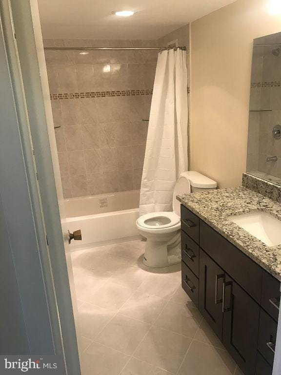 full bathroom featuring tile patterned flooring, vanity, shower / bath combo, and toilet