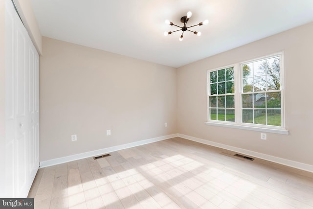 spare room featuring light hardwood / wood-style flooring and a notable chandelier