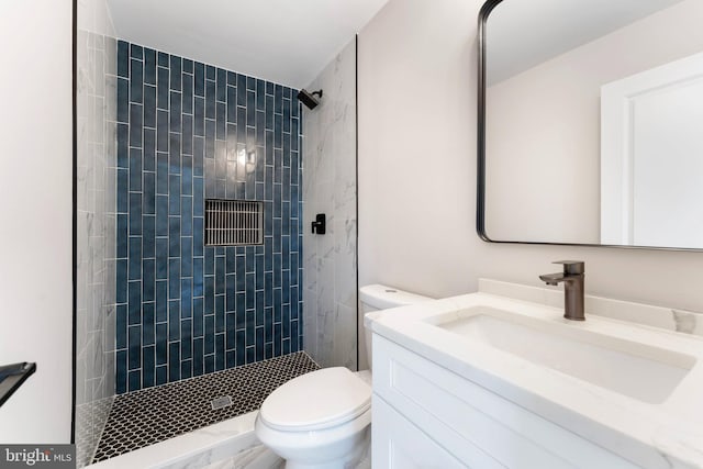 bathroom featuring vanity, toilet, and a tile shower