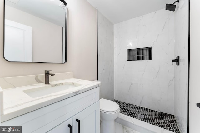 bathroom with vanity, toilet, and tiled shower