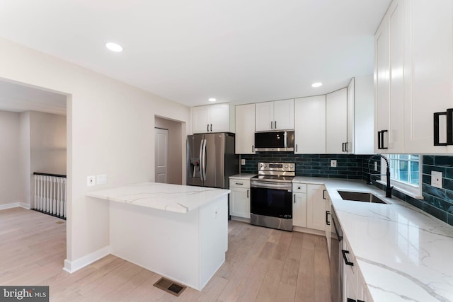 kitchen featuring sink, white cabinets, light wood-type flooring, and appliances with stainless steel finishes