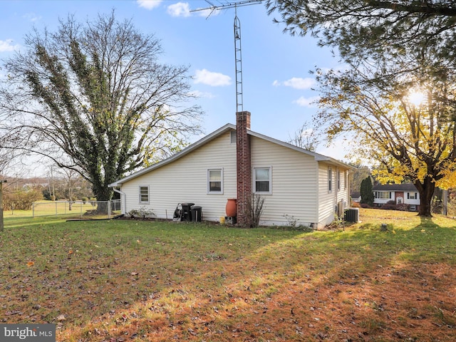 view of property exterior with cooling unit and a lawn