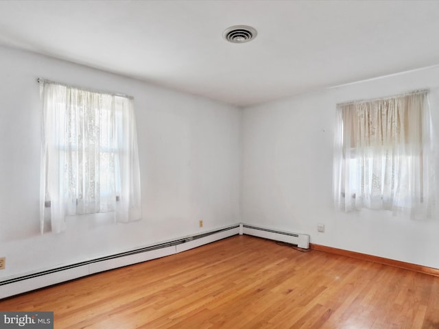 spare room featuring light wood-type flooring and a baseboard heating unit