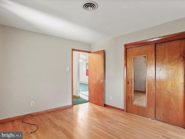 unfurnished bedroom with light wood-type flooring and a closet