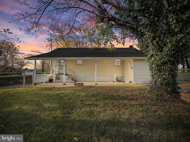 back house at dusk with a yard and a patio