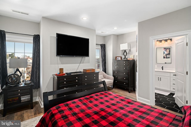 bedroom with dark hardwood / wood-style flooring, ensuite bathroom, and sink