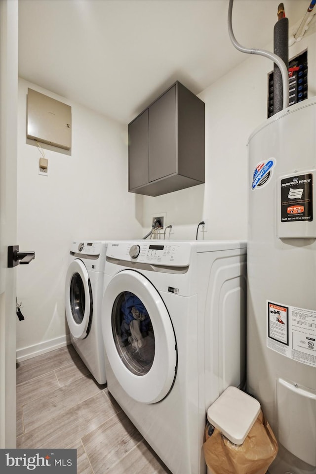 clothes washing area featuring cabinets, independent washer and dryer, and water heater