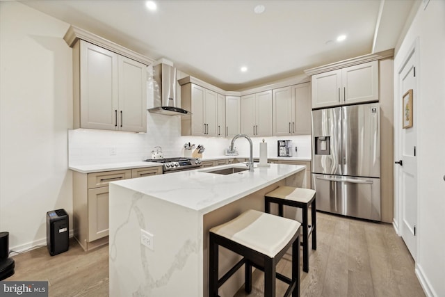 kitchen with sink, wall chimney exhaust hood, a center island with sink, and appliances with stainless steel finishes