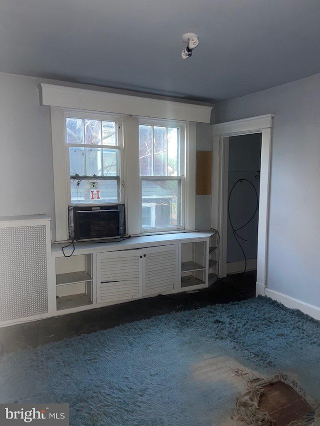 unfurnished living room featuring dark colored carpet, radiator heating unit, and cooling unit