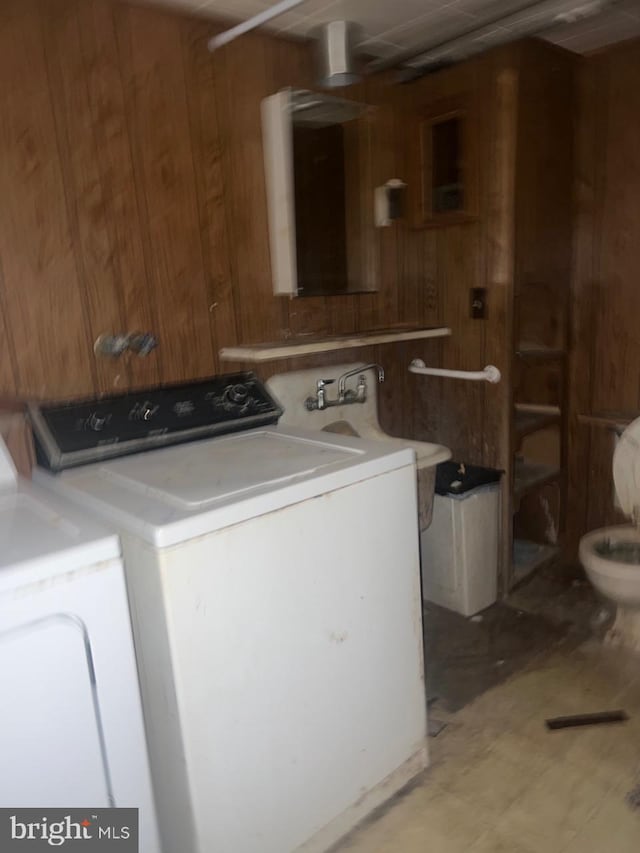 clothes washing area featuring wood walls and independent washer and dryer