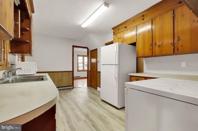 kitchen featuring sink, a baseboard radiator, light hardwood / wood-style flooring, white appliances, and wooden walls