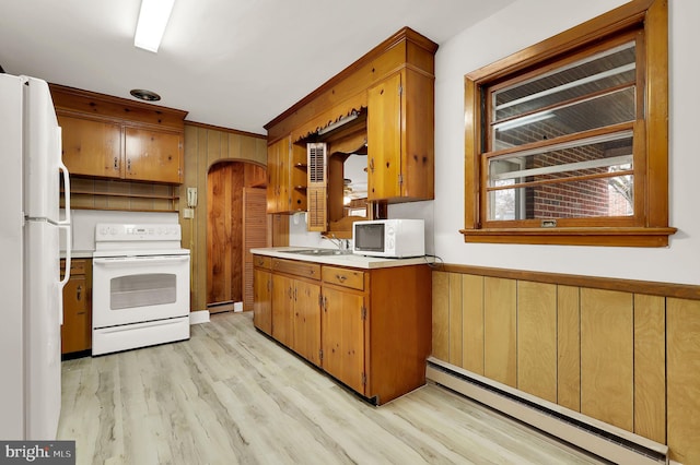 kitchen featuring wood walls, white appliances, crown molding, light wood-type flooring, and baseboard heating