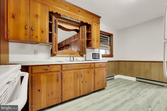 kitchen featuring sink, stove, light hardwood / wood-style floors, and a baseboard heating unit