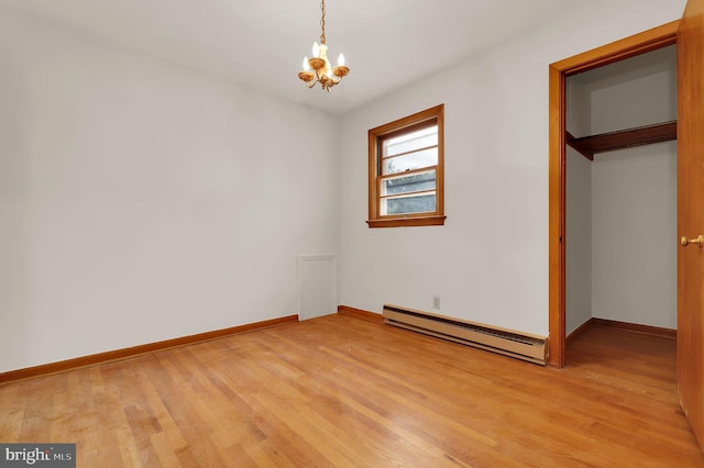 unfurnished bedroom featuring wood-type flooring, a closet, a baseboard heating unit, and a notable chandelier