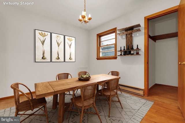 dining space featuring an inviting chandelier, light wood-type flooring, and a baseboard heating unit